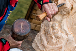 49853533 - hands of sculptor and hammer detail while carving wood